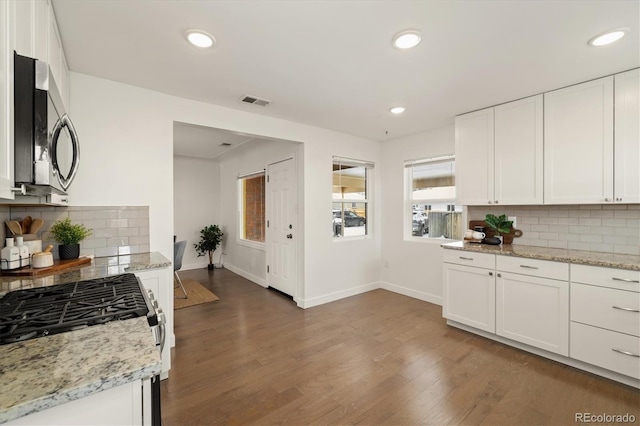 kitchen with stainless steel appliances, white cabinets, and light stone counters