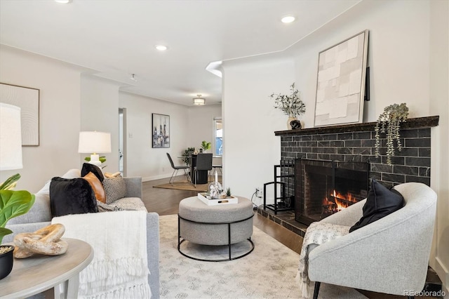 living room featuring a fireplace, baseboards, wood finished floors, and recessed lighting