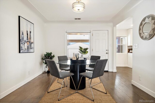 dining space with dark wood-style floors, visible vents, and baseboards