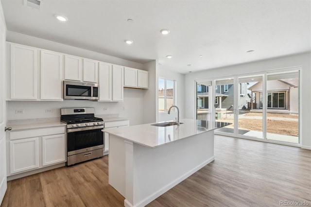 kitchen featuring a sink, light wood-style floors, appliances with stainless steel finishes, and white cabinets