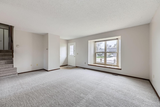 unfurnished living room featuring carpet flooring, a textured ceiling, visible vents, baseboards, and stairs