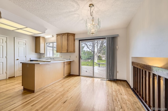 kitchen featuring a peninsula, light wood-type flooring, a chandelier, and a textured ceiling