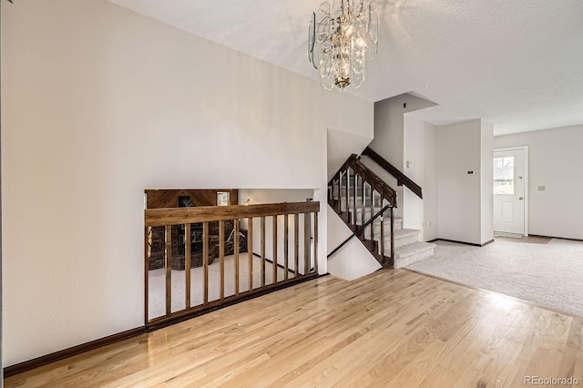 foyer featuring stairs, wood finished floors, a textured ceiling, an inviting chandelier, and baseboards