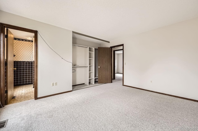 unfurnished bedroom featuring baseboards, carpet flooring, a closet, and ensuite bath