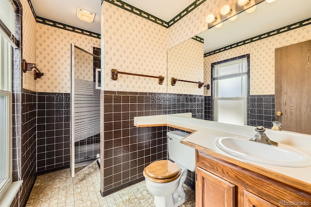 bathroom with tile walls, wallpapered walls, and a wainscoted wall