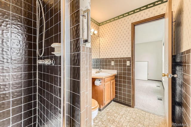 bathroom featuring tile walls, vanity, wallpapered walls, and wainscoting