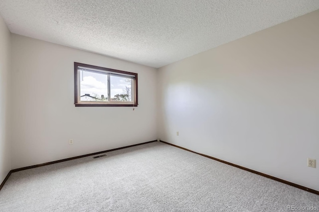 carpeted spare room with a textured ceiling, visible vents, and baseboards