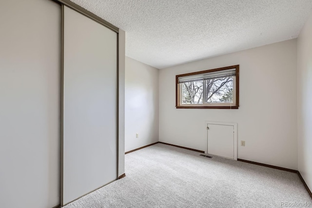unfurnished bedroom featuring a closet, carpet floors, a textured ceiling, visible vents, and baseboards