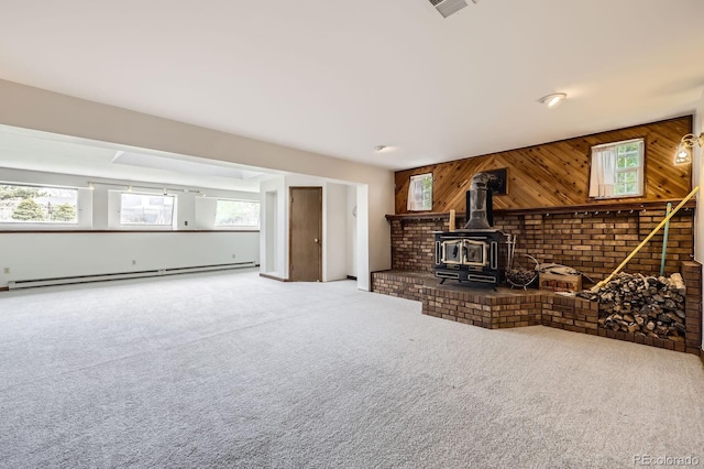 living room with a wood stove, carpet, visible vents, and a baseboard radiator