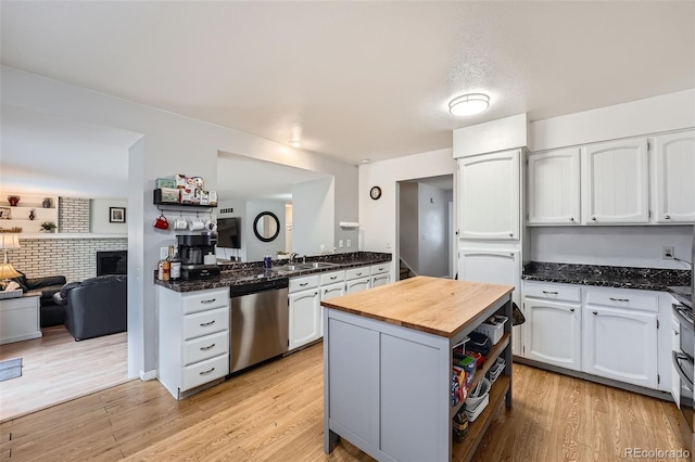 kitchen with stainless steel dishwasher, a sink, white cabinets, butcher block counters, and light wood-style floors