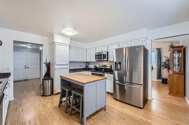 kitchen featuring butcher block countertops, a kitchen breakfast bar, light wood-type flooring, a center island, and stainless steel appliances