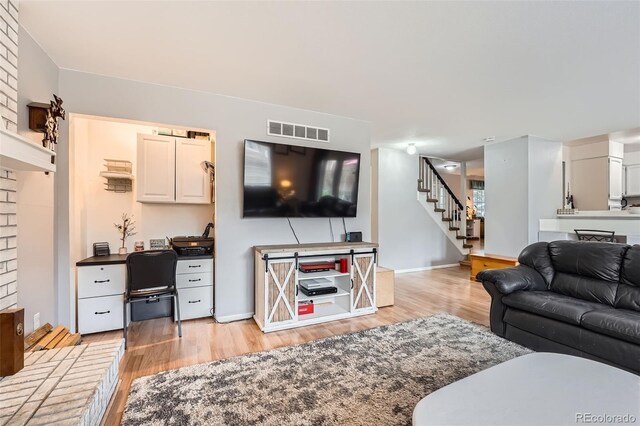 living room with light wood-style floors, baseboards, stairway, and visible vents