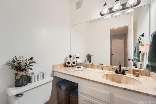 half bathroom featuring toilet, visible vents, and vanity