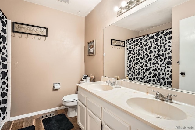 full bath featuring double vanity, a sink, wood finished floors, and toilet