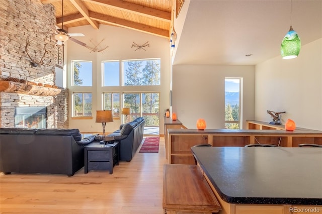 living room with ceiling fan, beam ceiling, high vaulted ceiling, a fireplace, and light hardwood / wood-style floors