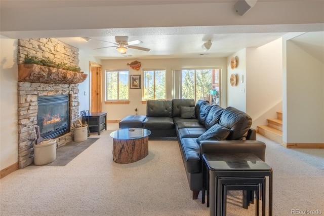 living room featuring ceiling fan, plenty of natural light, a stone fireplace, and carpet floors