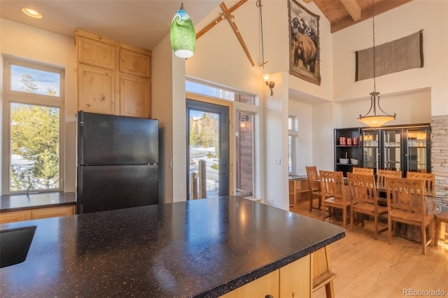 385 Trail Ridge Dr, Grand Lake, CO 80447 - kitchen with freestanding refrigerator, light brown cabinetry, light wood finished floors, a healthy amount of sunlight, and a towering ceiling