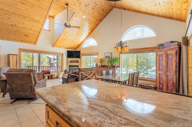 kitchen with decorative light fixtures, light tile patterned floors, wood ceiling, a stone fireplace, and ceiling fan with notable chandelier