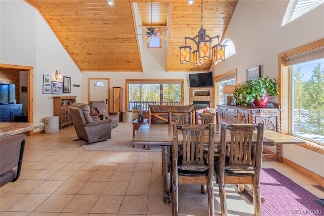 dining space with high vaulted ceiling, wooden ceiling, light tile patterned flooring, a fireplace, and a ceiling fan