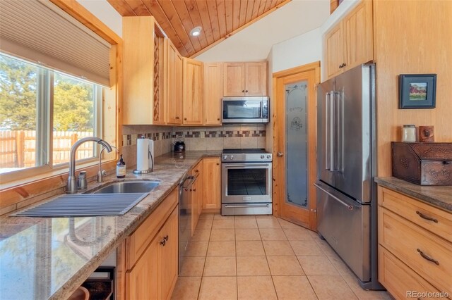 kitchen with light tile patterned floors, tasteful backsplash, appliances with stainless steel finishes, light brown cabinets, and a sink