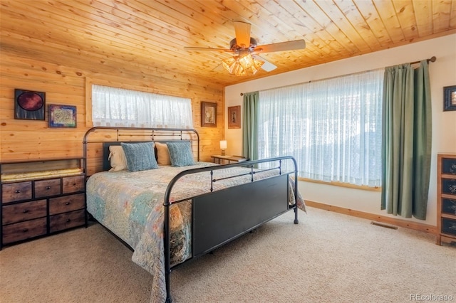 bedroom featuring wooden ceiling, wooden walls, carpet flooring, a ceiling fan, and visible vents