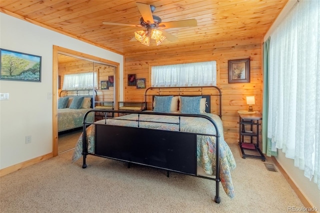 carpeted bedroom featuring visible vents, baseboards, wood ceiling, and wooden walls