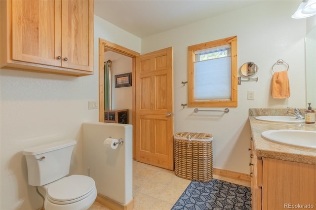 bathroom with double vanity, toilet, a sink, and tile patterned floors