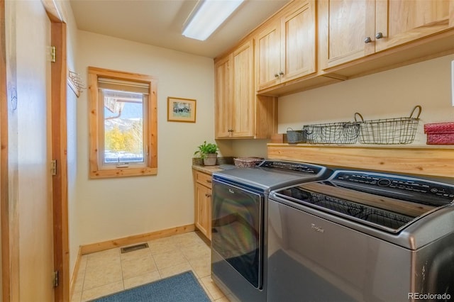 washroom with light tile patterned floors, visible vents, cabinet space, washer and dryer, and baseboards