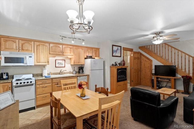 kitchen with light stone counters, sink, hanging light fixtures, white appliances, and light brown cabinetry