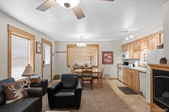 living room featuring light tile patterned flooring, ceiling fan with notable chandelier, sink, and rail lighting