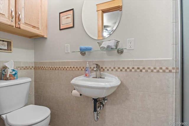 bathroom featuring sink, tile walls, and toilet