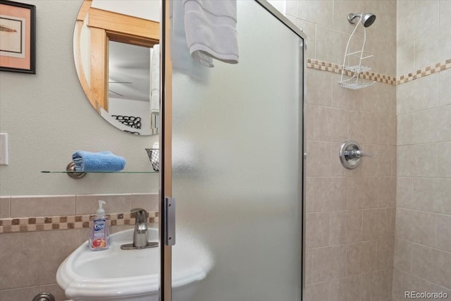 bathroom with tile walls, sink, and a shower with door