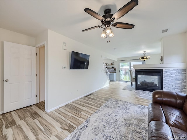 living room with a fireplace, light hardwood / wood-style floors, and ceiling fan