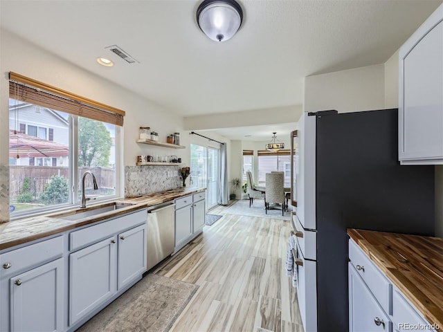 kitchen with dishwasher, a healthy amount of sunlight, butcher block counters, and fridge