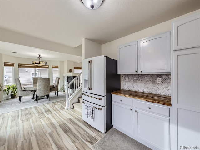 kitchen featuring backsplash, white cabinets, light wood-type flooring, high end fridge, and butcher block counters