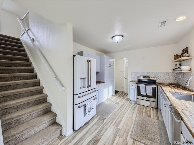 kitchen featuring wood counters, stainless steel appliances, sink, light hardwood / wood-style floors, and white cabinetry