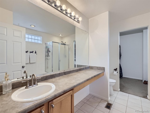 bathroom with tile patterned flooring, vanity, a shower with door, and toilet