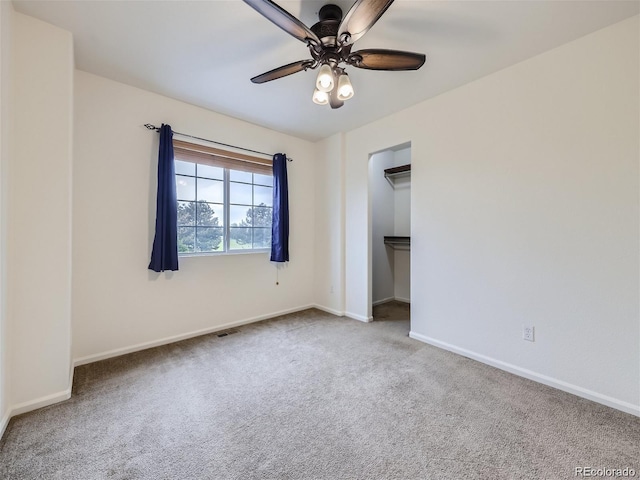 unfurnished bedroom featuring ceiling fan, a closet, carpet floors, and a spacious closet