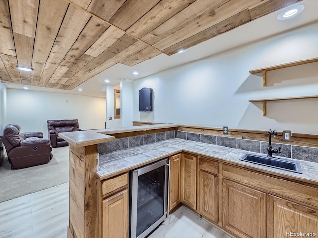 kitchen featuring sink, wine cooler, kitchen peninsula, wood ceiling, and light wood-type flooring