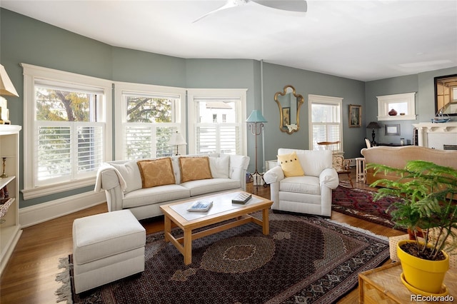 living area with wood finished floors, a ceiling fan, and baseboards