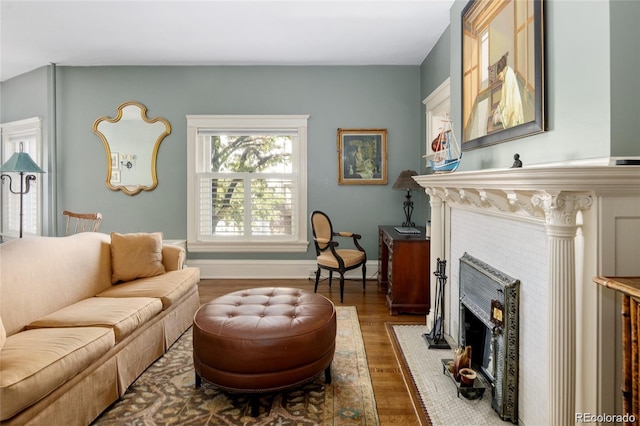 living room featuring baseboards, a tiled fireplace, and wood finished floors