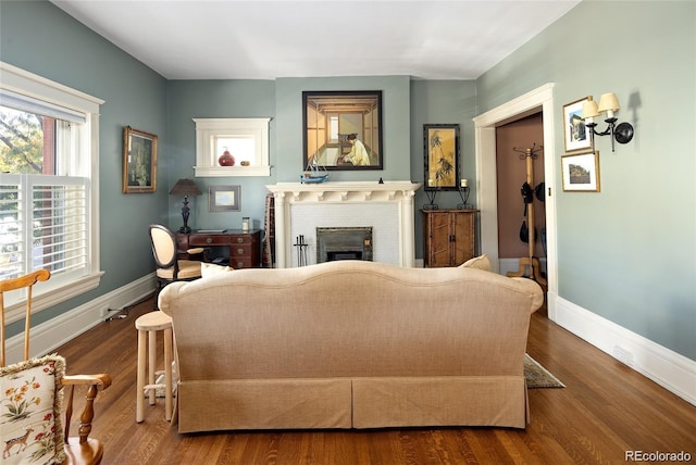 living area with a brick fireplace, baseboards, and wood finished floors