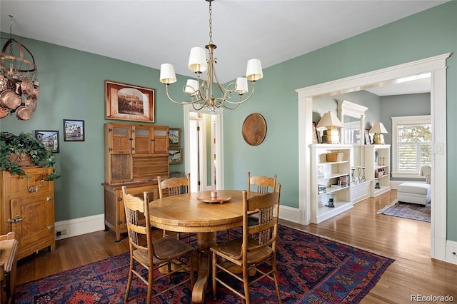 dining area featuring a notable chandelier, baseboards, and wood finished floors