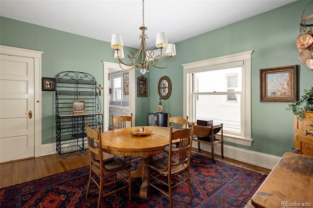 dining room featuring dark wood-type flooring, a chandelier, and baseboards