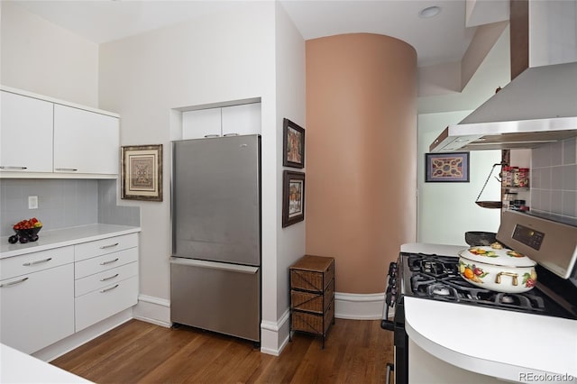 kitchen featuring appliances with stainless steel finishes, light countertops, wall chimney range hood, and tasteful backsplash