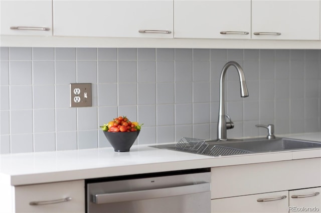 kitchen with tasteful backsplash, light countertops, dishwasher, and a sink