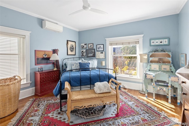 bedroom with ornamental molding, a wall unit AC, baseboards, and wood finished floors