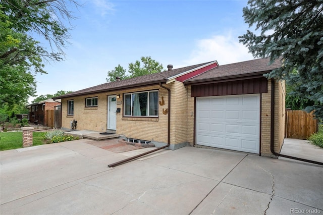 ranch-style home featuring a garage, fence, concrete driveway, and brick siding