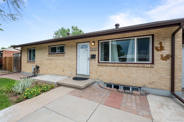 ranch-style home featuring fence, a patio, and brick siding