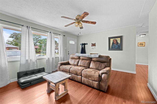 living room featuring a ceiling fan, a textured ceiling, baseboards, and wood finished floors